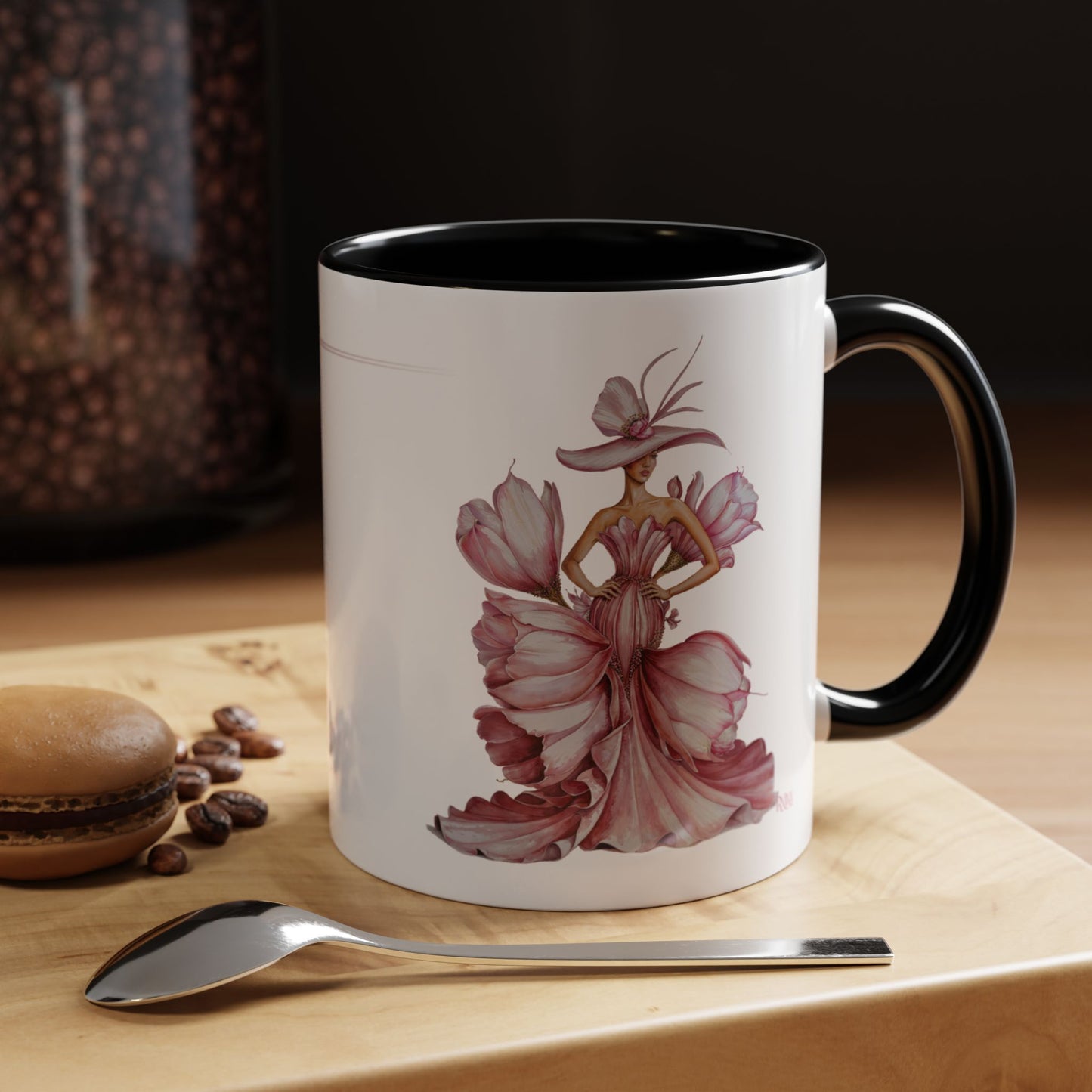 Mug with artistic design of a woman in a dress on a wooden surface with coffee beans and a spoon.