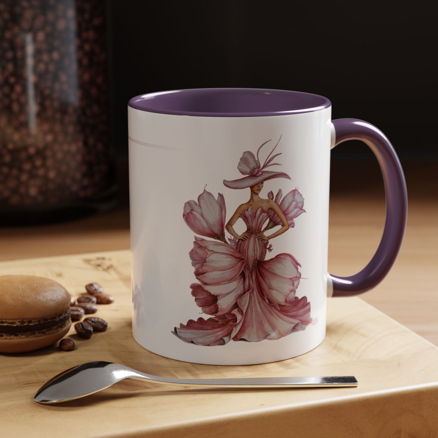 Mug with artistic design of a woman in a dress on a wooden surface with coffee beans and a spoon.