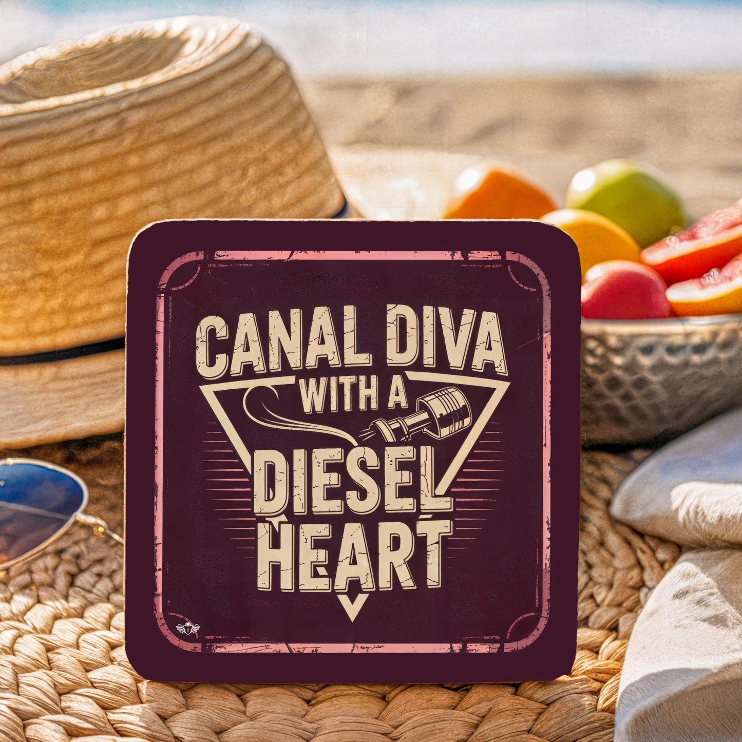 Coaster with "Canal Diva with a Diesel Heart" text on a woven surface with fruit in the background