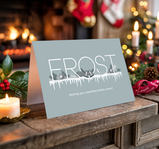"Frost" holiday card on a wooden surface with festive background