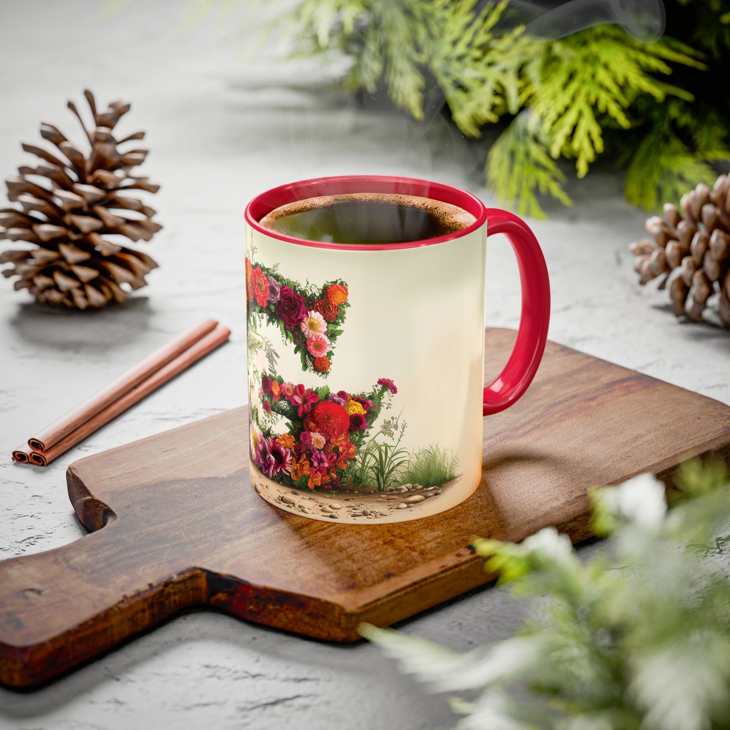 Mug with floral design on a wooden board with pine cones and cinnamon sticks.