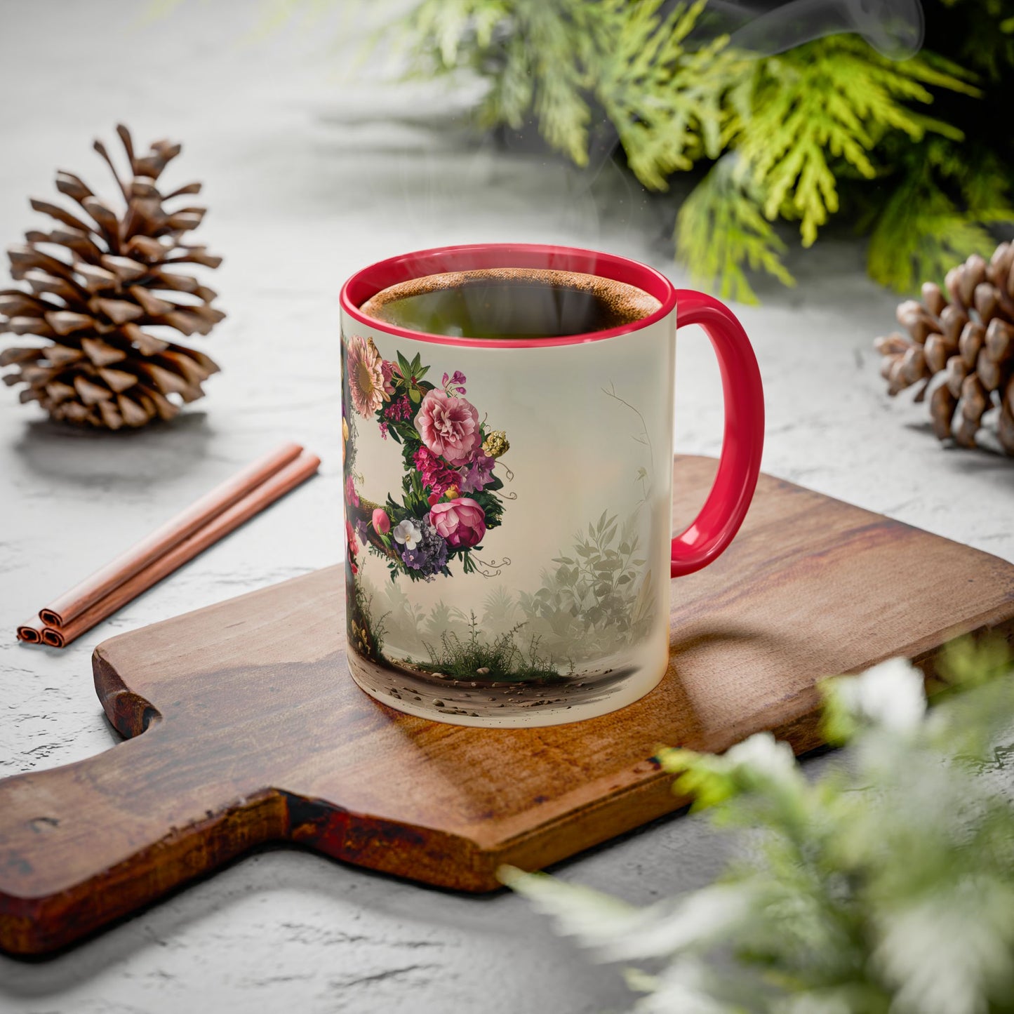 Mug with floral design on a wooden board with cinnamon sticks and pine cones.