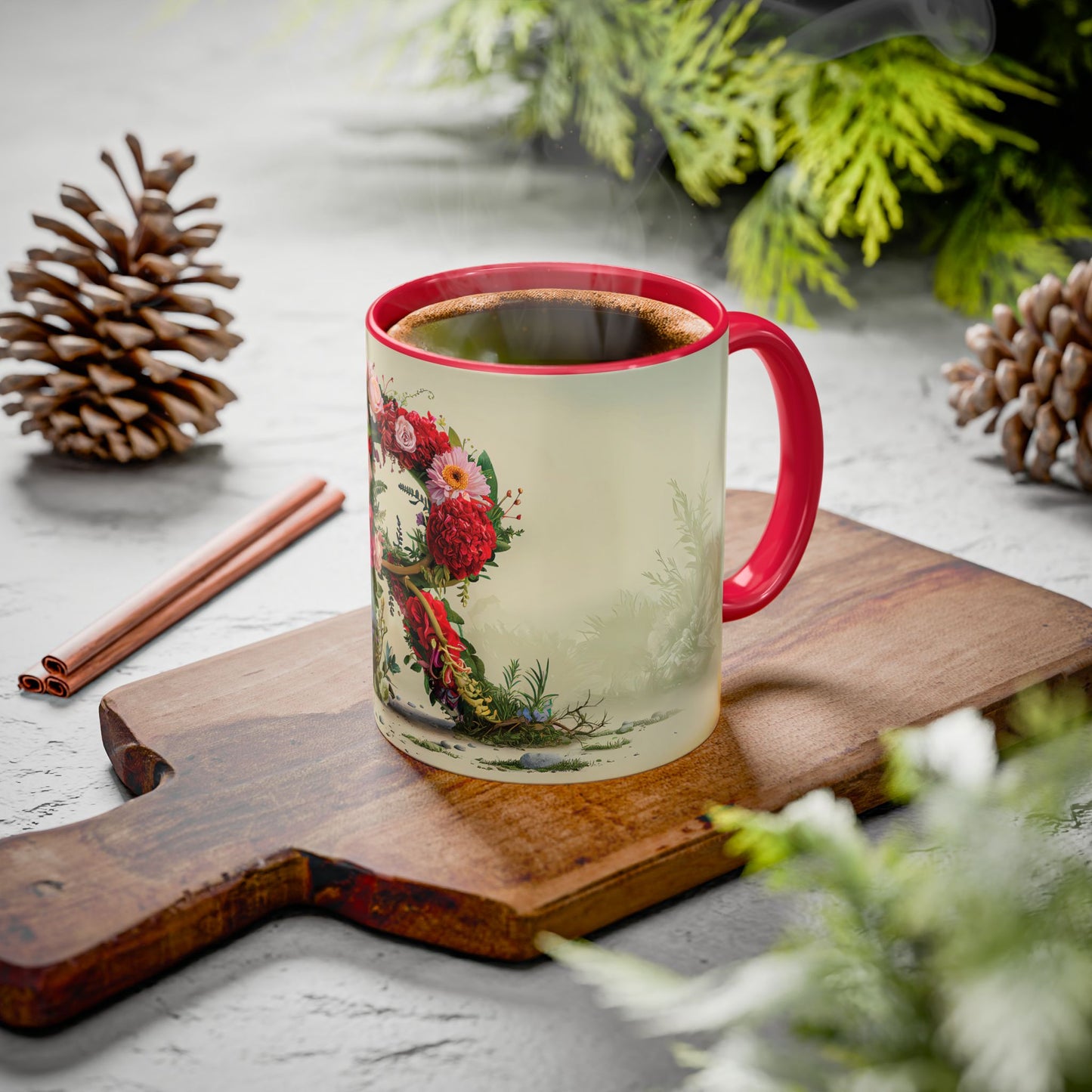 Decorative mug with floral design on a wooden board with pine cones and cinnamon sticks.