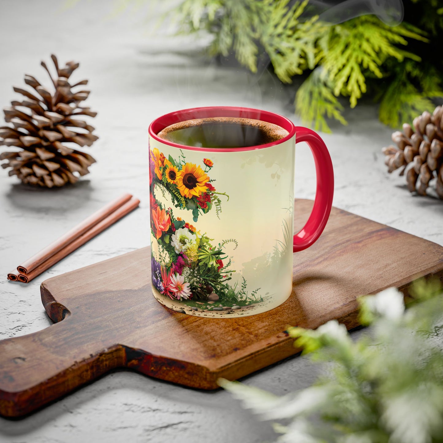 Mug with floral design on a wooden board with cinnamon sticks and pine cones.