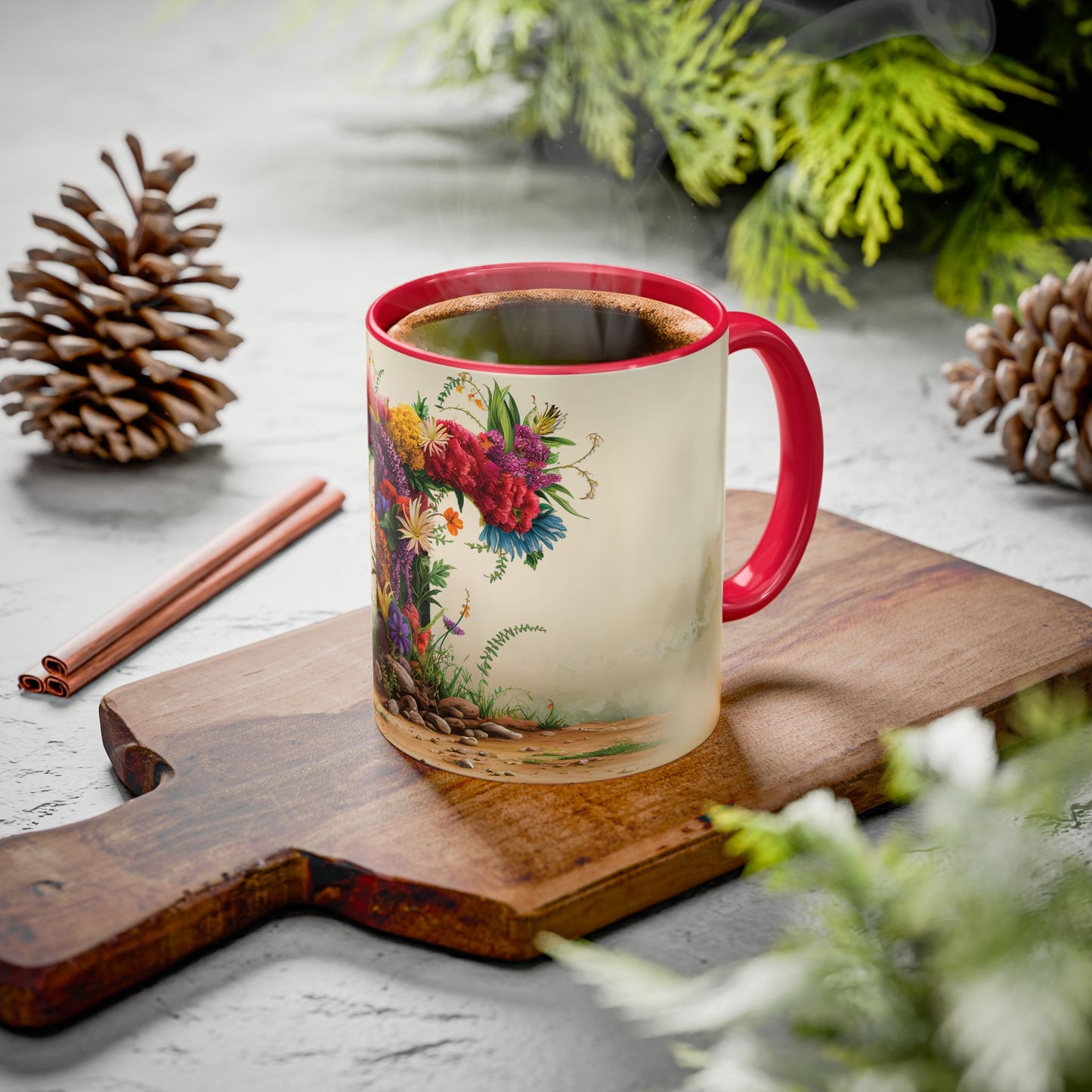 Mug with floral design on a wooden board with cinnamon sticks and pine cones.