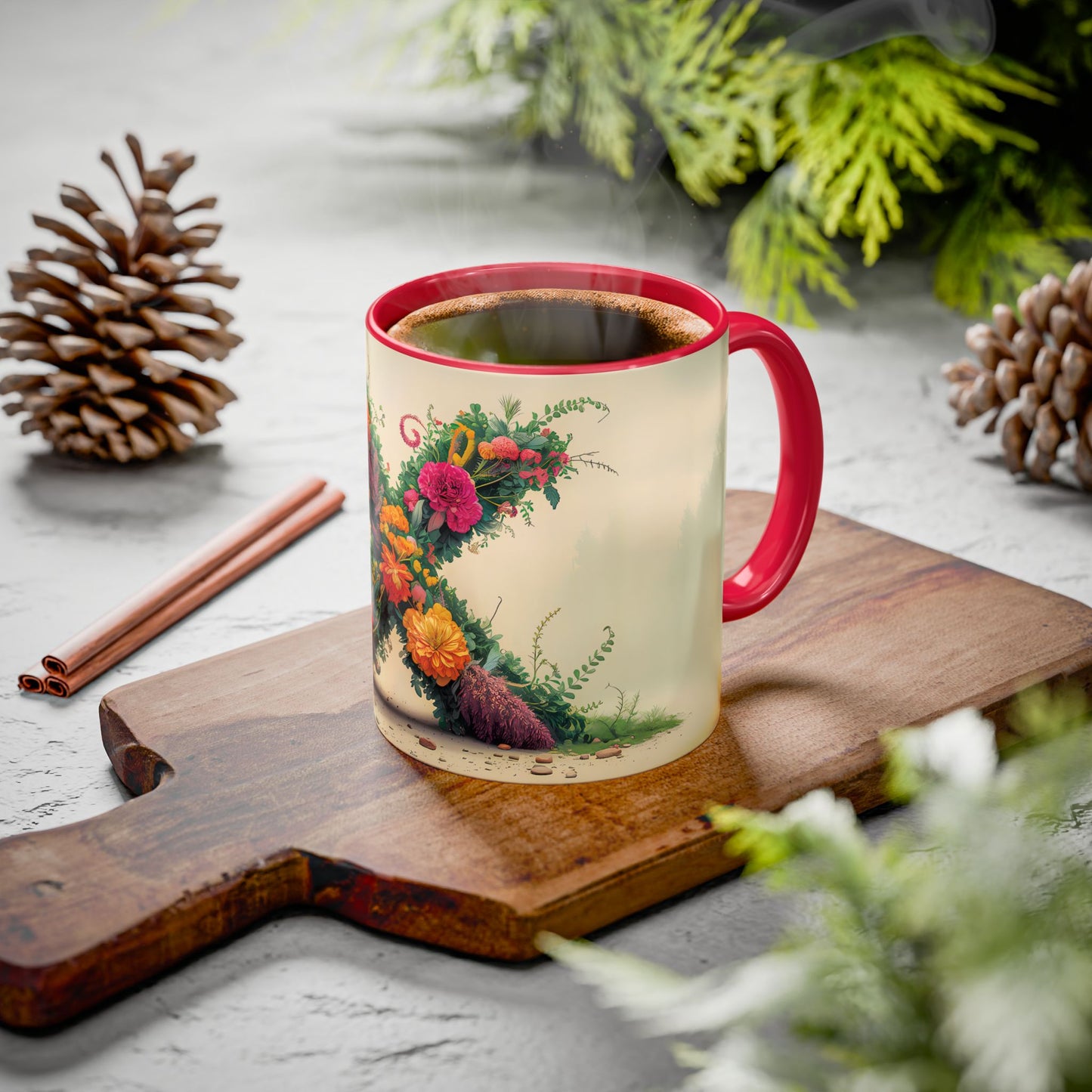 Decorative mug with floral design on a wooden board with pine cones and cinnamon sticks.