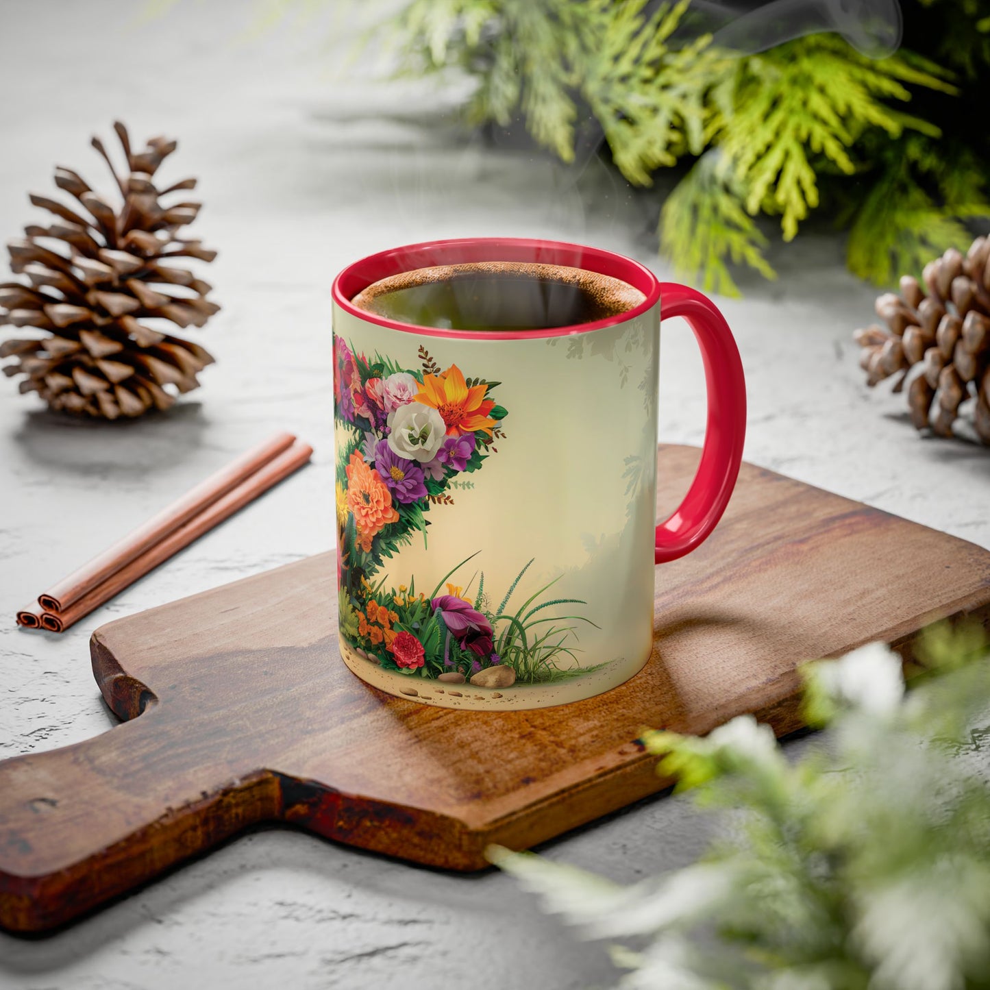Mug with floral design on a wooden board with cinnamon sticks and pine cones.