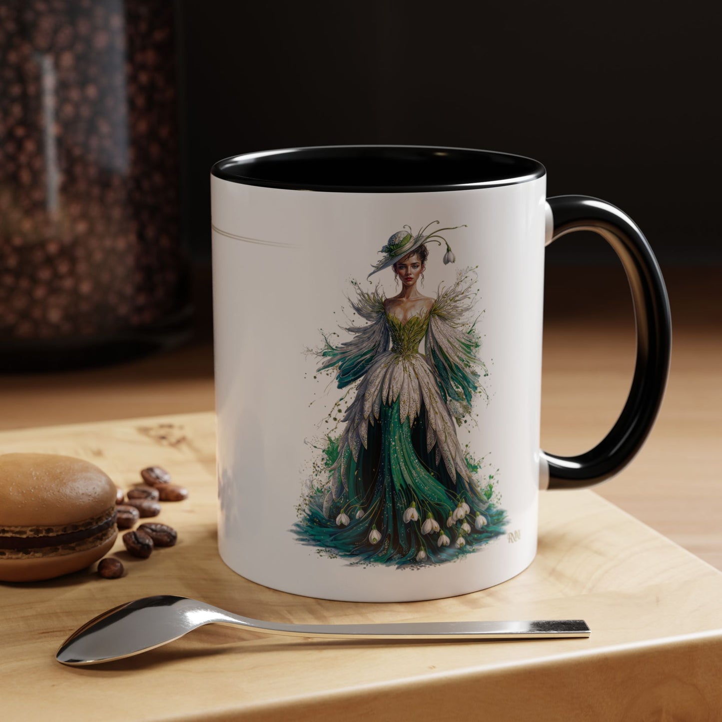 Mug with a decorative design of a woman in a green dress on a wooden surface with coffee beans and a spoon.