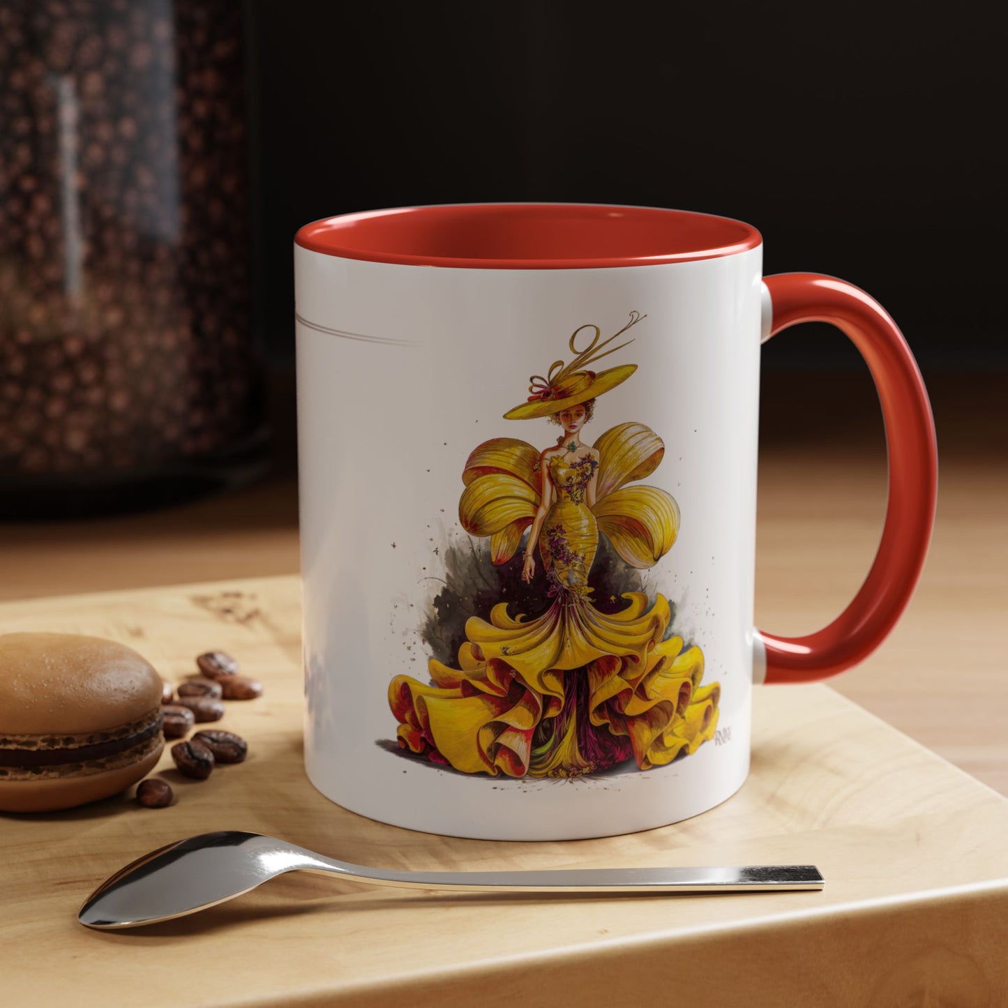 Mug with a colorful design of a woman in a yellow dress on a wooden surface with coffee beans and a spoon.