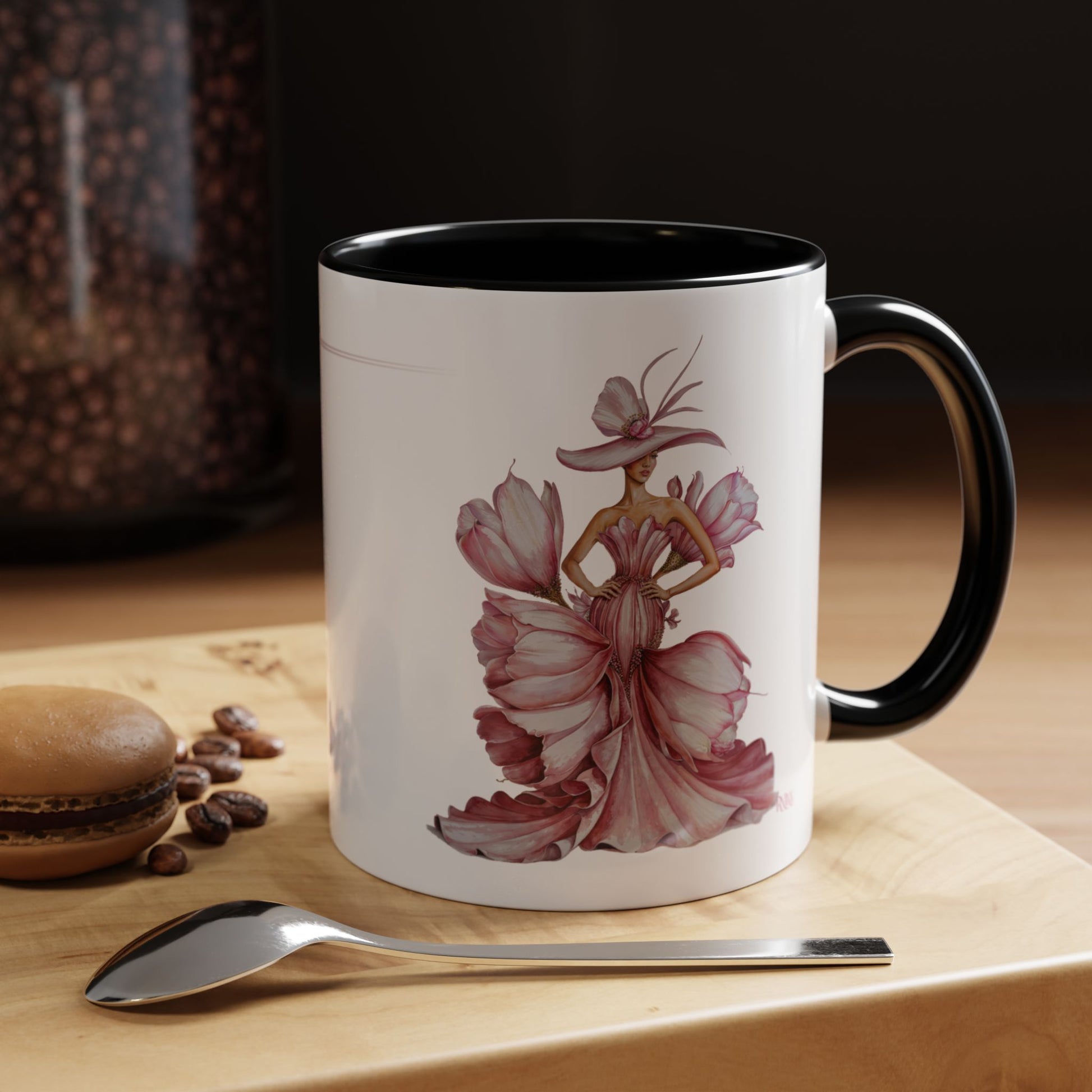 Mug with artistic design of a woman in a dress on a wooden surface with coffee beans and a spoon.