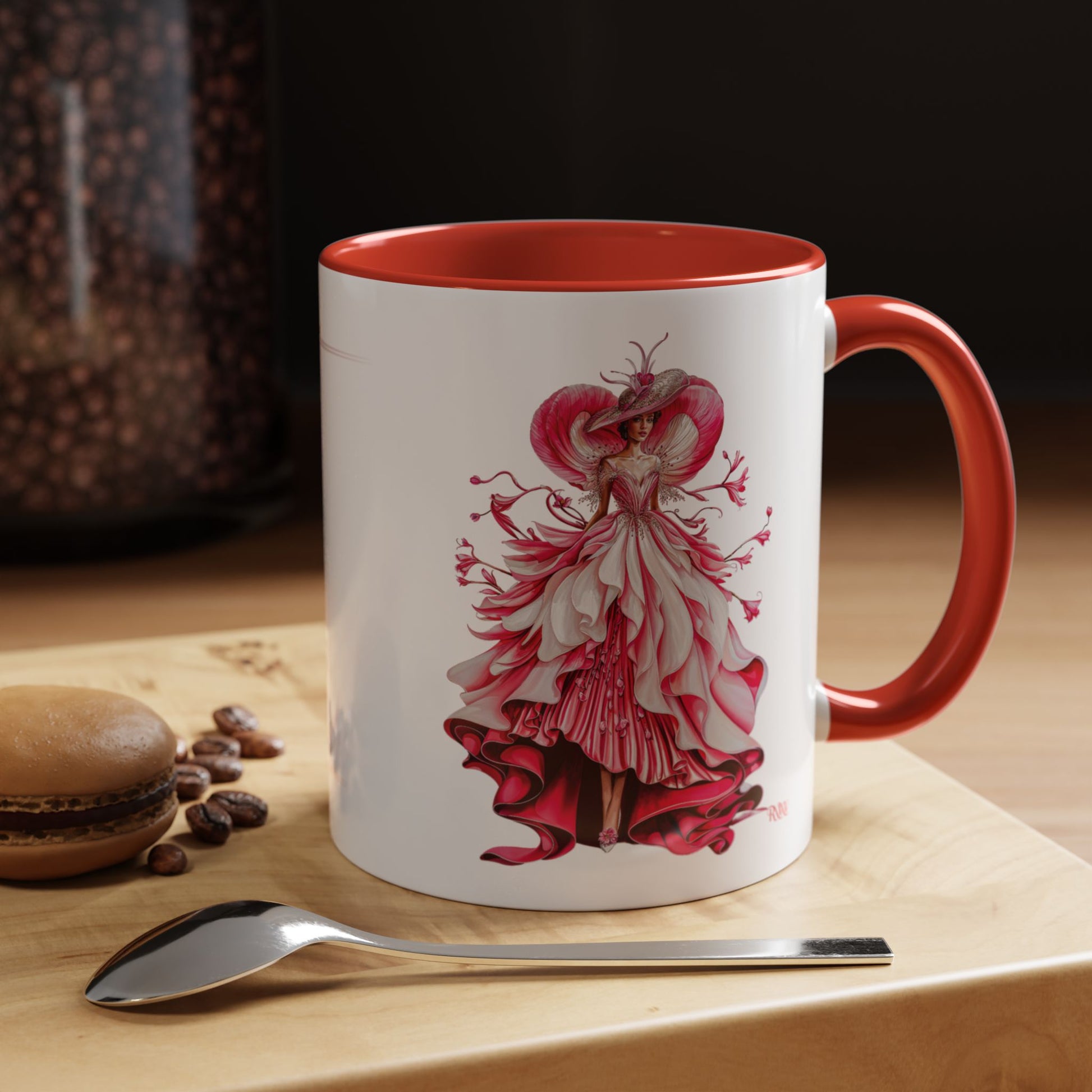 Mug with a red and white dress design on a wooden surface with coffee beans and a spoon.