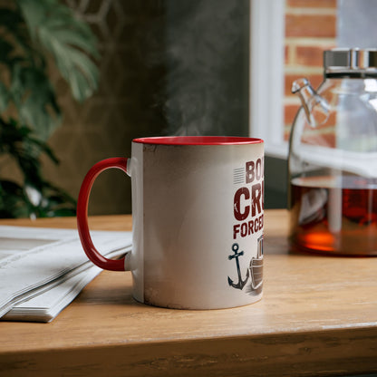 White mug with red interior and handle on a wooden surface, featuring text and an anchor design.