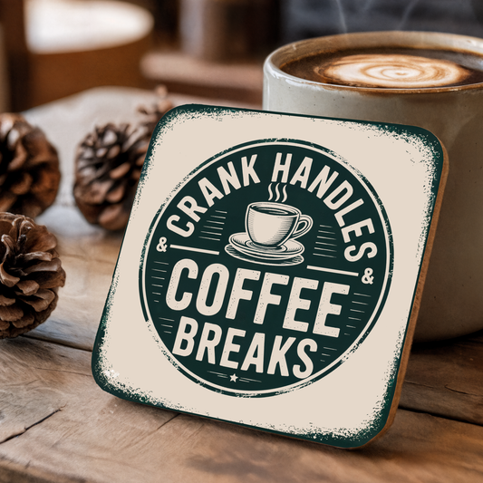 Coaster with "Crank Handles & Coffee Breaks" text next to a cup of coffee on a wooden surface.