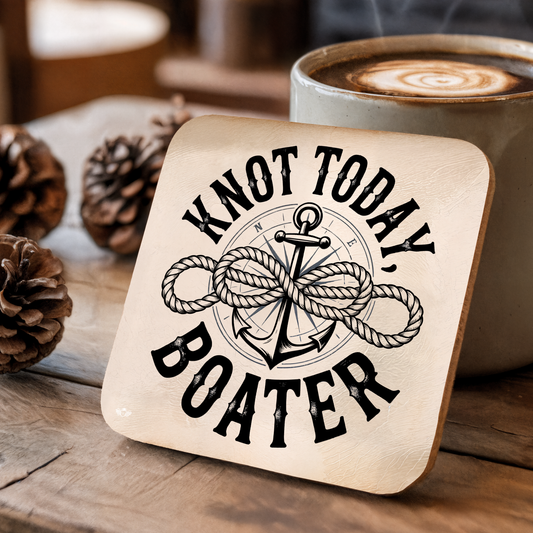 Coaster with "Knot Today, Boater" design on a wooden surface with a coffee cup and pinecones.