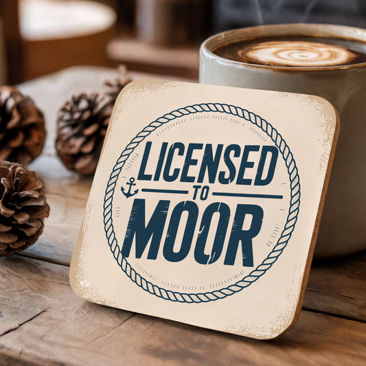 Coaster with "Licensed to Moor" text on a wooden surface with a coffee cup and pinecones.