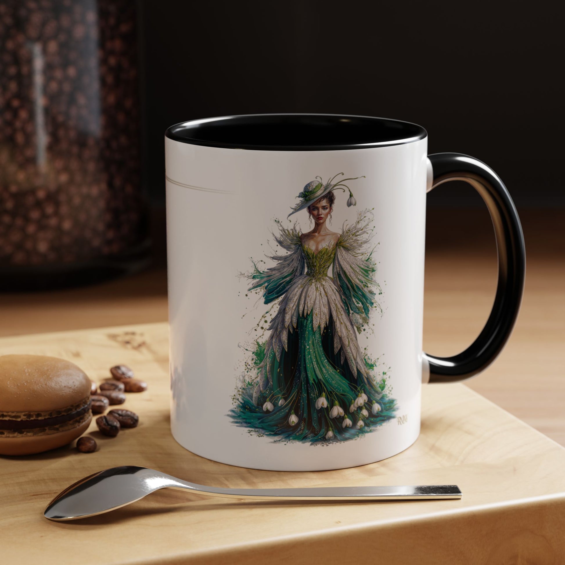 Mug with a decorative design of a woman in a green dress on a wooden surface with coffee beans and a spoon.