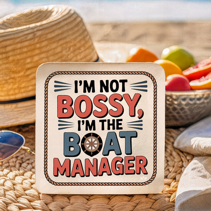 Coaster with "I'm not bossy, I'm the boat manager" text on a woven surface with fruit in the background