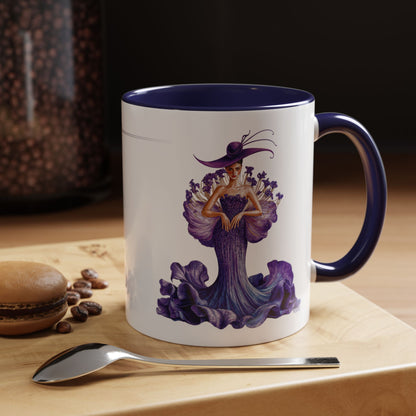 Mug with a decorative design of a woman in a purple dress and hat on a wooden surface with coffee beans and a spoon.